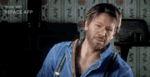 a man with a beard is wearing a blue shirt and suspenders and looking at the camera .