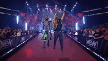 two men are walking down a red carpet in front of a aew wall