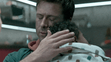 a man holding a baby in his arms with his eyes closed