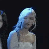 a woman in a white dress is standing next to another woman in a black background .