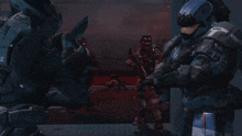 a group of soldiers are standing in a dark room and one of them is wearing a helmet with a t on it