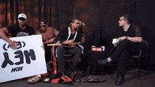a group of men sitting around a table with a sign that says hey on it