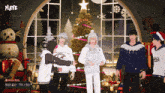 a group of people standing in front of a christmas tree with playe written on the bottom left