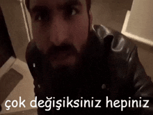 a man with a beard is wearing a black leather jacket and has the words " çok degisiksiniz hepiniz " written below him
