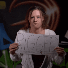 a woman is holding up a sign that says rigged