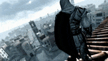 a man in a hooded cape stands on a roof overlooking a city