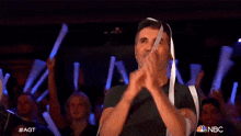 a man in a black shirt is dancing in front of a crowd with nbc written on the bottom left