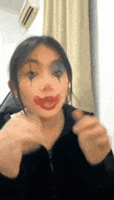 a girl with a clown face painted on her face is making a funny face .