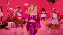 a woman in a purple dress is standing in front of candy canes