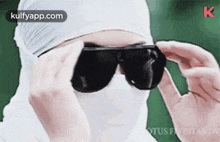 a person wearing a white mask and sunglasses is covering their face .