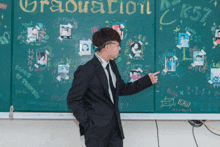 a man in a suit stands in front of a blackboard that says graduation on it