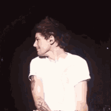 a man in a white shirt is standing on a stage in the dark