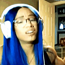 a woman with blue hair is wearing headphones and making a face