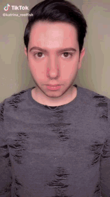 a young man with a nose ring is wearing a gray shirt