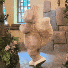 a teddy bear dressed as a squirrel is dancing in a room with flowers .