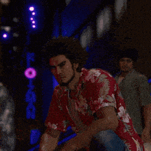 a man in a red shirt with flowers on it is pointing at someone