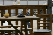 a man smoking a cigarette behind a wooden table