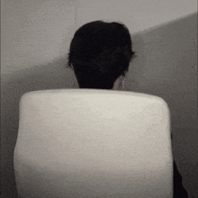 a person sitting in a white chair with their head behind the back