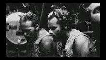 a black and white photo of a group of men in a room