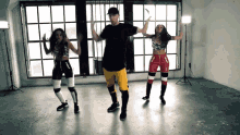 a man and two women are dancing in a room with a lot of windows