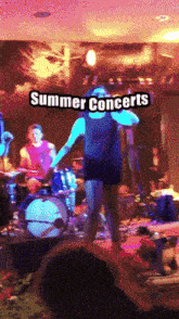 a man stands on a stage with the words summer concerts written above him