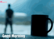 a blurred image of a man standing next to a cup of coffee with the words good morning written on the bottom