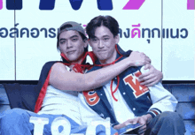 a man in a varsity jacket with the letter y on it is hugging another man