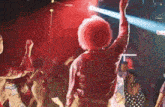 a man with pink hair is dancing in a crowd of people