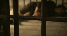 a person behind bars in a jail cell with their head down