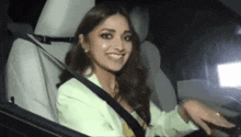 a woman is sitting in the back seat of a car with a seat belt on .