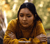 a woman wearing a yellow sweatshirt with the word cheeseburgers on it