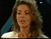 a woman with curly hair is making a funny face on a tv screen .