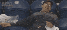a man is laying in a stadium with a onegif.com logo on the bottom left