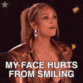 a woman is sitting in front of a microphone and says her face hurts from smiling