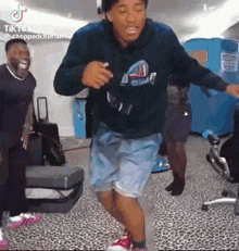 a man in a hoodie and shorts is dancing in a room .