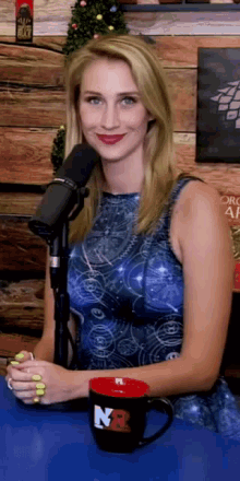 a woman is sitting in front of a microphone next to a mug that says n3