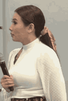 a woman in a white top is holding a microphone in her hand