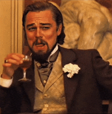 a man in a suit and tie is holding a glass of wine
