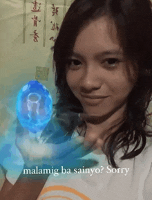 a woman holding a blue object with the words malamig ba sainyo sorry written below her