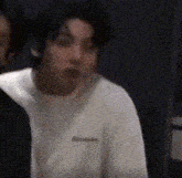 a man in a white shirt is making a funny face while standing next to another man .