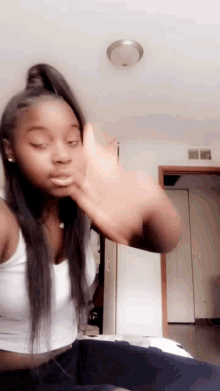 a woman in a white tank top is making a face
