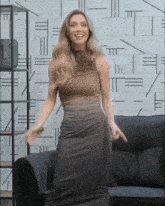 a woman in a brown dress is standing in front of a wall with a pattern of lines