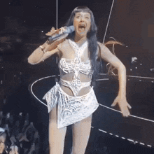 a woman is singing into a microphone on a stage while wearing a white dress .