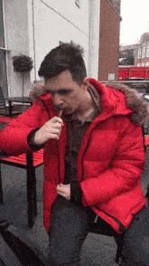 a man in a red jacket smoking a cigarette