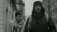 a man wearing a ny sweatshirt walks down the street