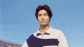 a man in a blue and white striped shirt looks at the camera