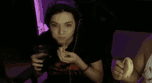 a woman is sitting in a chair eating a sandwich and drinking a glass of soda .