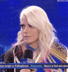 a woman with blonde hair is talking into a microphone on a wrestling show .