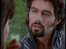 a man with a beard and earrings is looking at a woman .