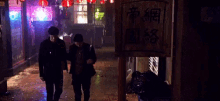a couple walking down a street with chinese writing on a sign
